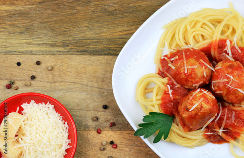 Cucina italiana. Spaghetti con polpette, salsa al pomodoro e parmegiano grattugiato su tavolo di legno rustico. Vista dall'alto photo