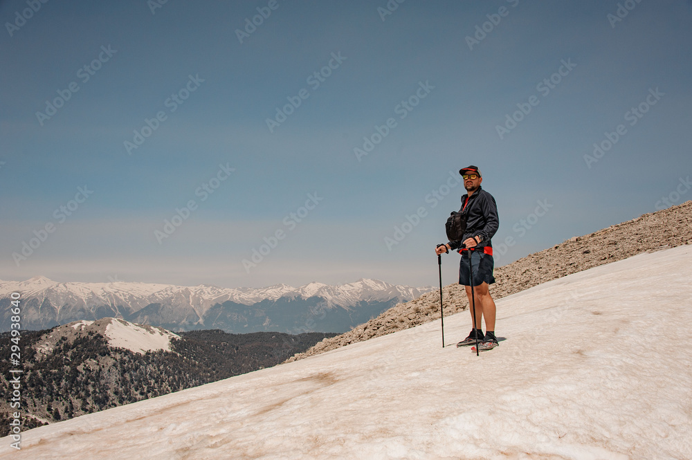 Man standing on the dirty snow on the Tahtali mountain with hiking sticks