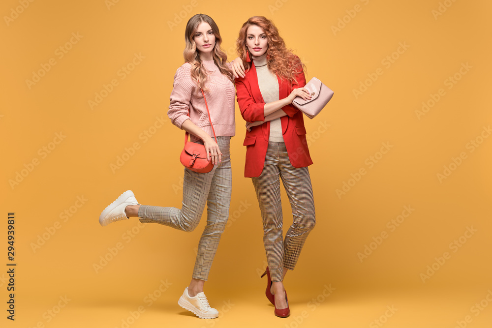 Fashionable autumn woman with stylish hairstyle, makeup dance. Two Shapely blonde redhead girl having fun, trendy red pink outfit, fashion hair. Gorgeous female model, beauty funny concept