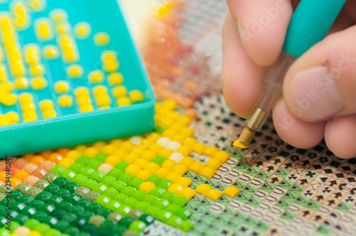 Collecting diamond embroidery, diamond mosaic. Colored crystals. Needlework. Creation. CloseUp.