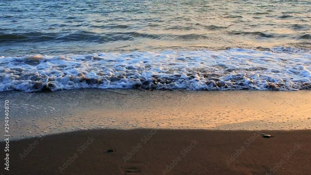 Sea wave rolls ashore close-up, low angle view, slow motion footage sunrise or sunset time Sea wave rolls ashore close-up, low angle view, slow motion footage sunrise or sunset time