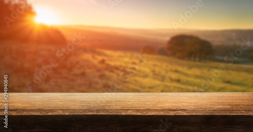 Obraz na płótnie A wooden table top product display with a blurred background scene of golden sunset fields. w salonie