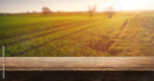 Obraz na płótnie A wooden table top product display with a blurred background scene of farmland at sunset. w salonie