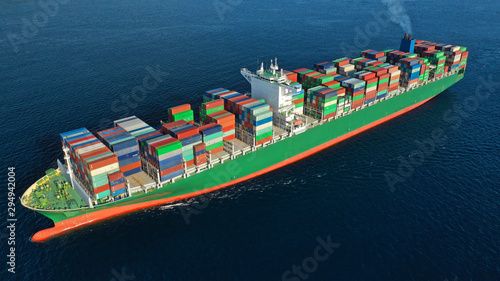 Aerial drone photo of Container cargo Ship carrying load in truck-size colourful containers cruising in deep blue Mediterranean sea 