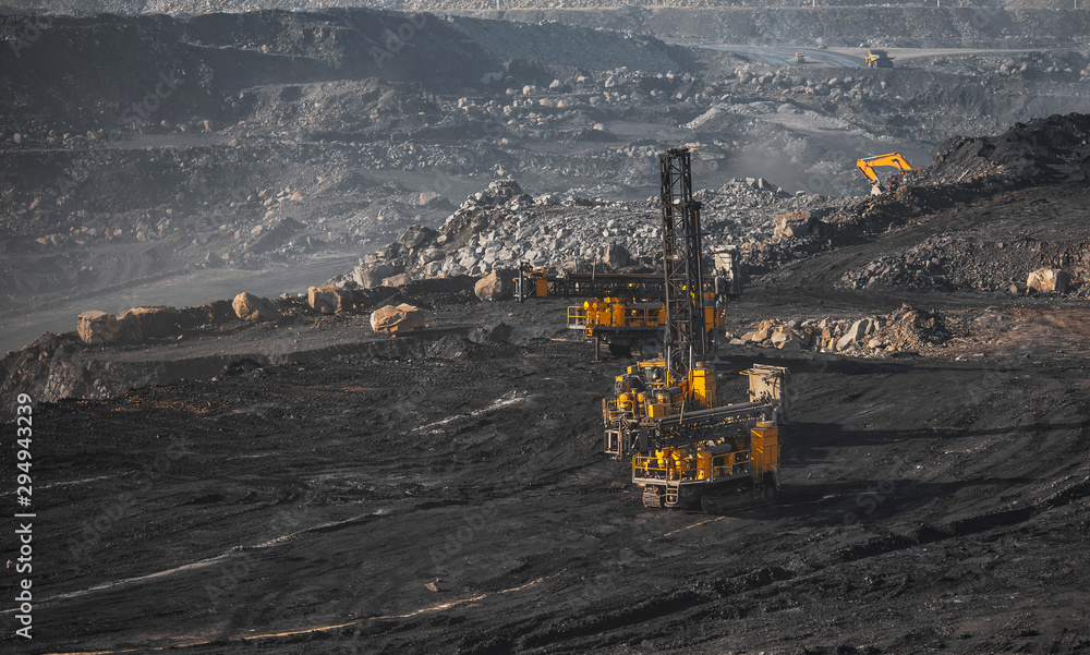 Open coal mine. Drilling machine borer installing cast explosives blasting Open coal mine. Drilling machine borer installing cast explosives blasting