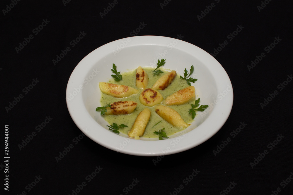 Homemade potato gnocchi with a blue cheese sauce, in a white plate. with black background. 