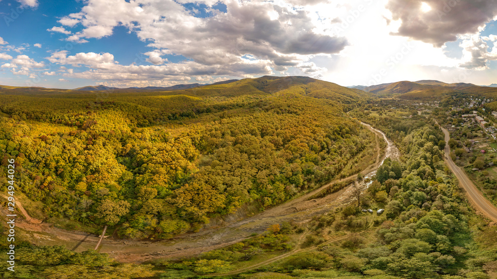 Autumn mountain landscape near the mountain river Hable in the mountains of the Western Caucasus in the south of Russia. The river dried up by the autumn, the suspension bridge. Aerial view of yellow 