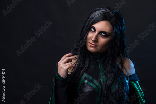 Beautiful cosplay woman in a halloween costume with green cloak.