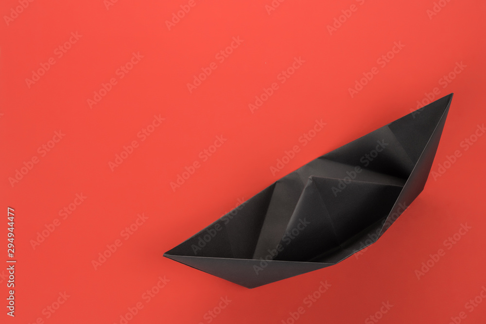 Black paper boat top view on red background Black paper boat top view on red background