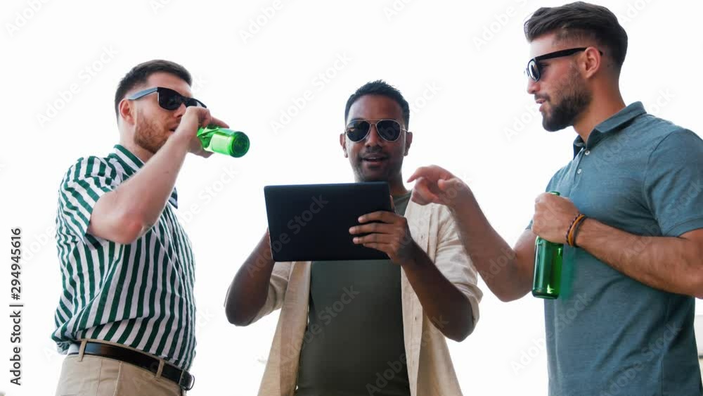 leisure, technology and people concept - happy male friends with tablet computer drinking beer and talking at rooftop party in summer leisure, technology and people concept - happy male friends with tablet computer drinking beer and talking at rooftop party in summer