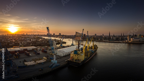 Die Elbphilharmonie im Hafen von Hamburg bei Sonnenuntergang mit Containerschiff im Vordergrund