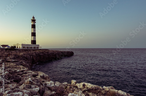 Blue hour view of the Cap Artrutx Lighthouse or Artrutx Lighthouse, an active 19th century lighthouse located on the low-lying headland of the same name on the Spanish island of Menorca.