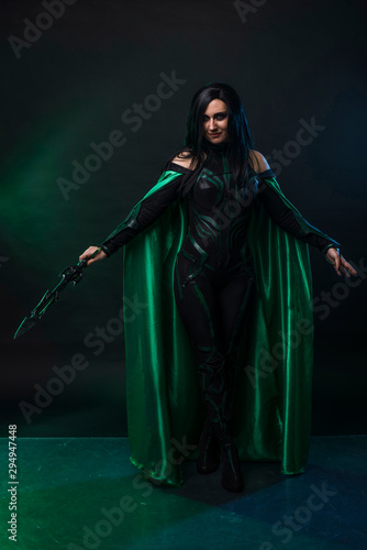 Beautiful cosplay woman in a halloween costume with green cloak.