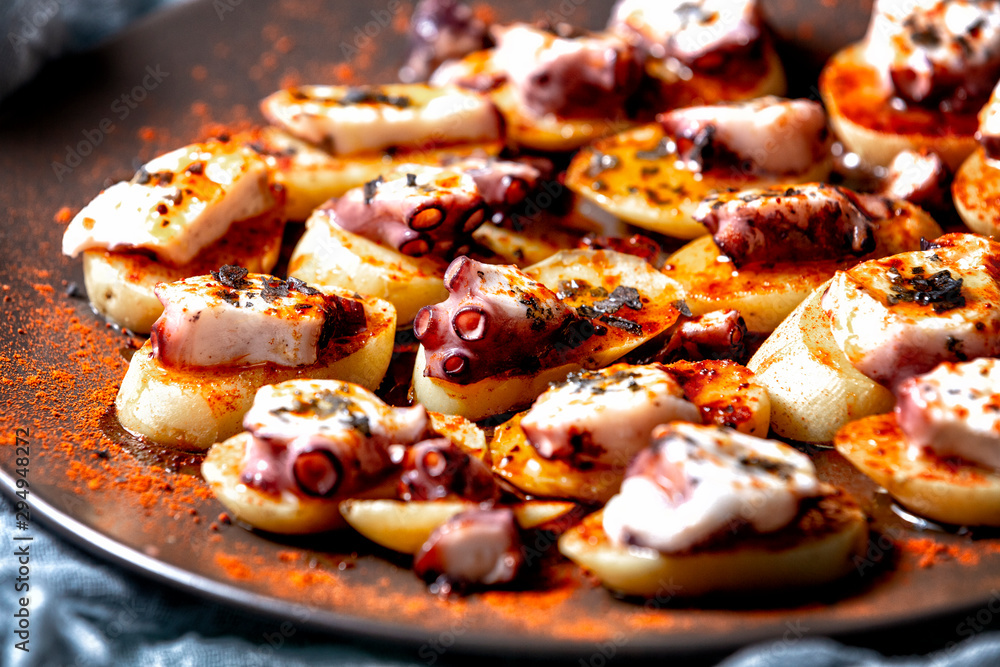 Octopus cooked Galician style, with potatoes and red pepper. Typical Spanish food dish, close-up view. Octopus cooked Galician style, with potatoes and red pepper. Typical Spanish food dish, close-up view.