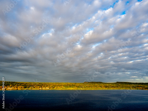 Horizon of stratocumulus clouds over golden land and dark blue sea photo
