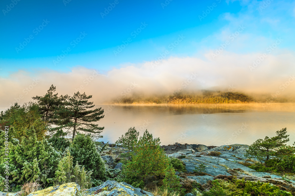 Fototapeta premium Landscape at sunrise at Kalvo Fjord as seen from truck parking lot at Uddevallavägen near village Saten, municipality of Orust in landscape Bohuslän province Västra Götalands län in Sweden.