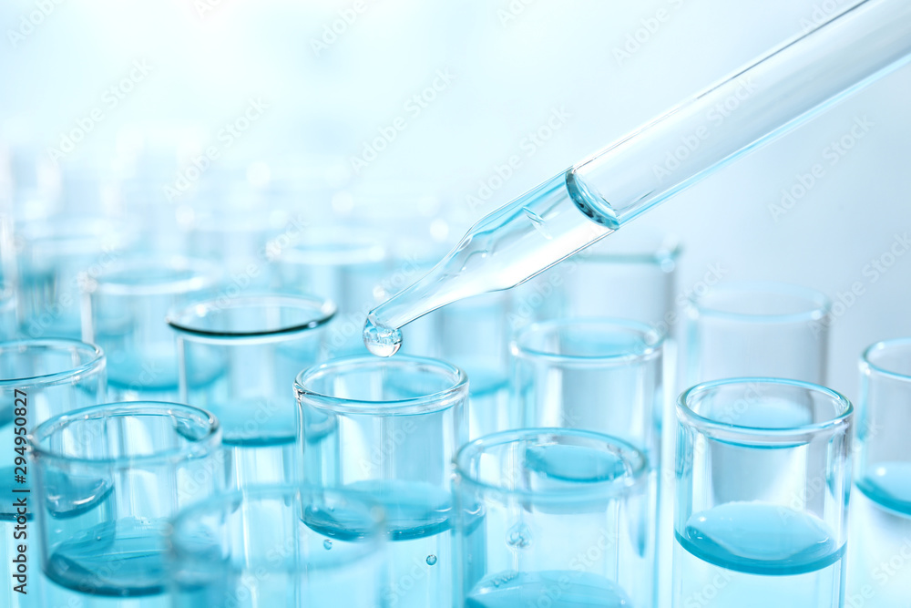 Dropping sample into test tube with light blue liquid, closeup Dropping sample into test tube with light blue liquid, closeup