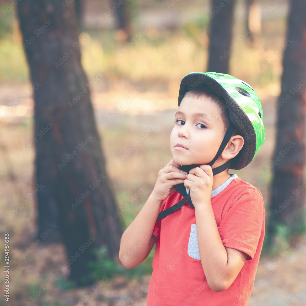 Boy in a helmet for cycling. Child puts on a bicycle helmet. Protective equipment for sports. Toned image. Boy in a helmet for cycling. Child puts on a bicycle helmet. Protective equipment for sports. Toned image.