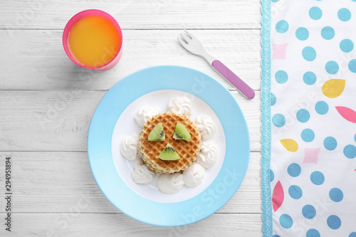 Tasty waffles served with whipped cream and juice on white wooden table, flat lay. Creative idea for kids breakfast