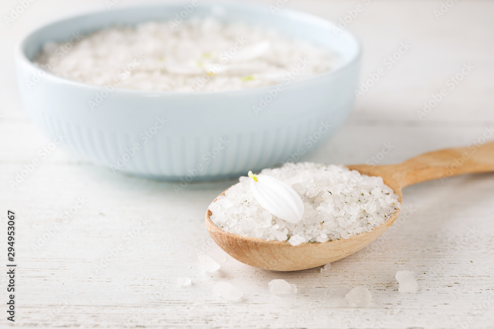 Spoon with sea salt for spa scrubbing procedure and petal on wooden table Spoon with sea salt for spa scrubbing procedure and petal on wooden table