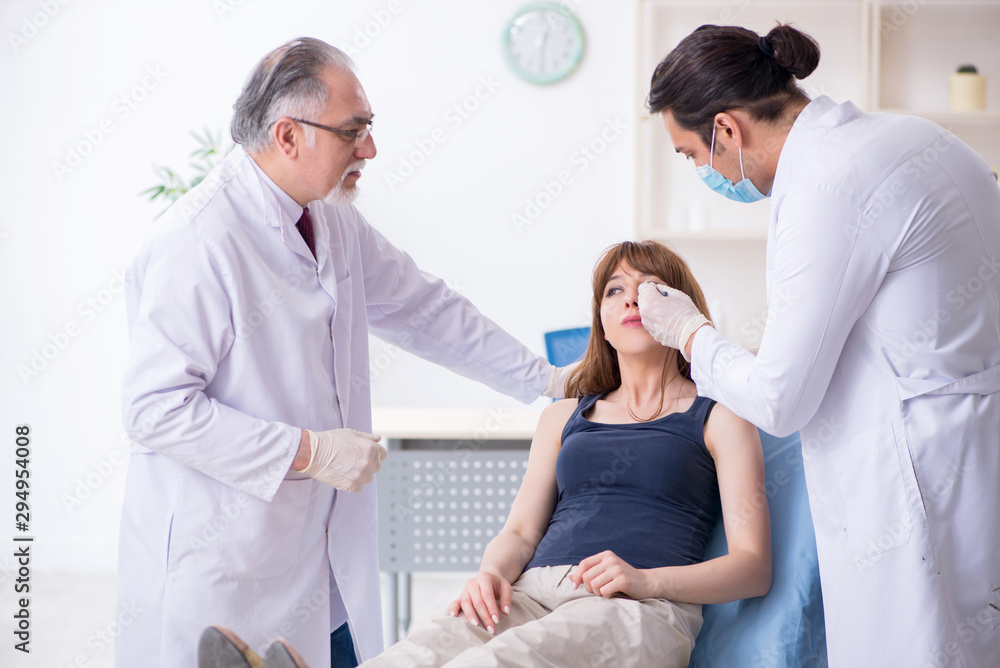 Fototapeta premium Two male doctors and young woman in plastic surgery concept