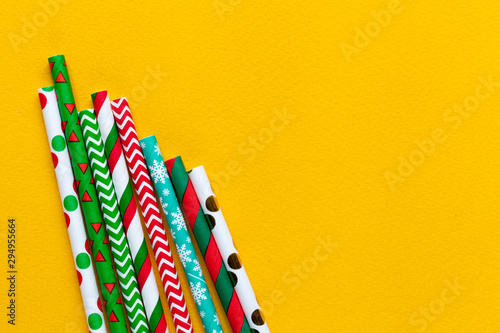 Colorful tubules with christmas ornament on yellow background, flat lay