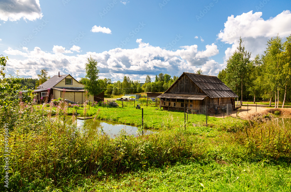 Obraz premium Village house with outbuildings and small pond