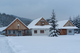 Wooden houses covered with fresh snow. in the foreground a christmas tree. Christmas winter mood.