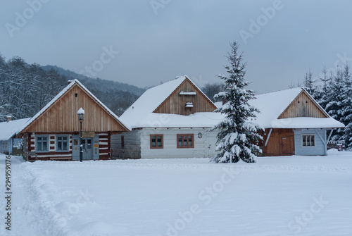 Wooden houses covered with fresh snow. in the foreground a christmas tree. Christmas winter mood.