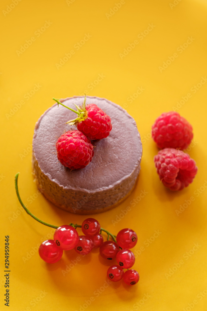 Tasty dessert cheesecake with raspberries and currants on a yellow background. Flat lay food Tasty dessert cheesecake with raspberries and currants on a yellow background. Flat lay food
