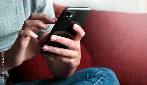 Frau Jugendliche Teenager mit Handy smartphone beim posten, chaten, tippen und schreiben in social media zuhause auf dem Sofa mit mobile phone eine Nachricht tippen. photo