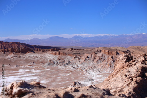  Crater with colored soil in Atacama desert, Chile. In the background mountains in the diffuse horizon with blue sky