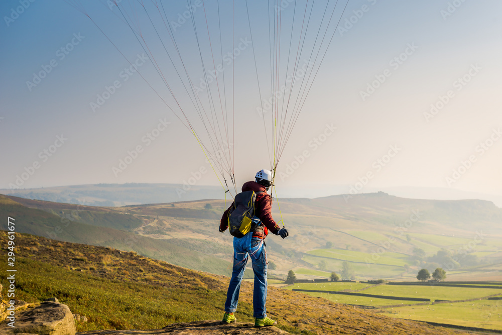 Obraz premium A man paragliding over the Stanage Edge in Derbyshire.
