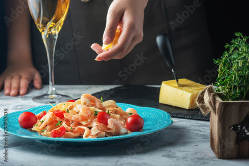 Fototapeta Naklejka Na Ścianę i Meble -  Mafaldine with tomato sauce and rosemary. Girl sprinkles pasta with cheese. Tasty dinner.