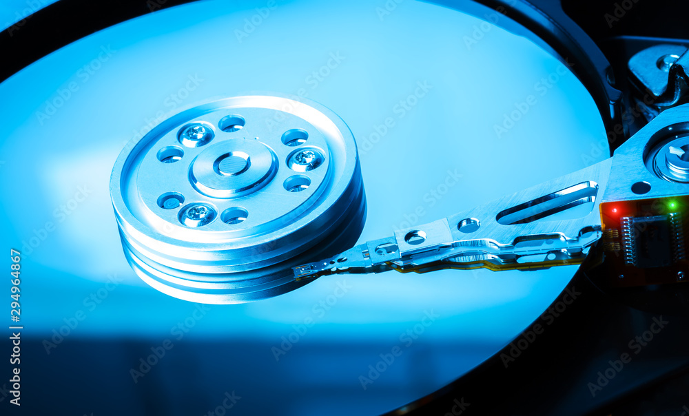 Close up inside of hard disk drive. Detail of writing/reading head on acuator arm and axis. Blue Toned Image. Close up inside of hard disk drive. Detail of writing/reading head on acuator arm and axis. Blue Toned Image.
