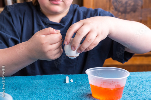 Child dipping an easter egg into a vat of color for dyeing