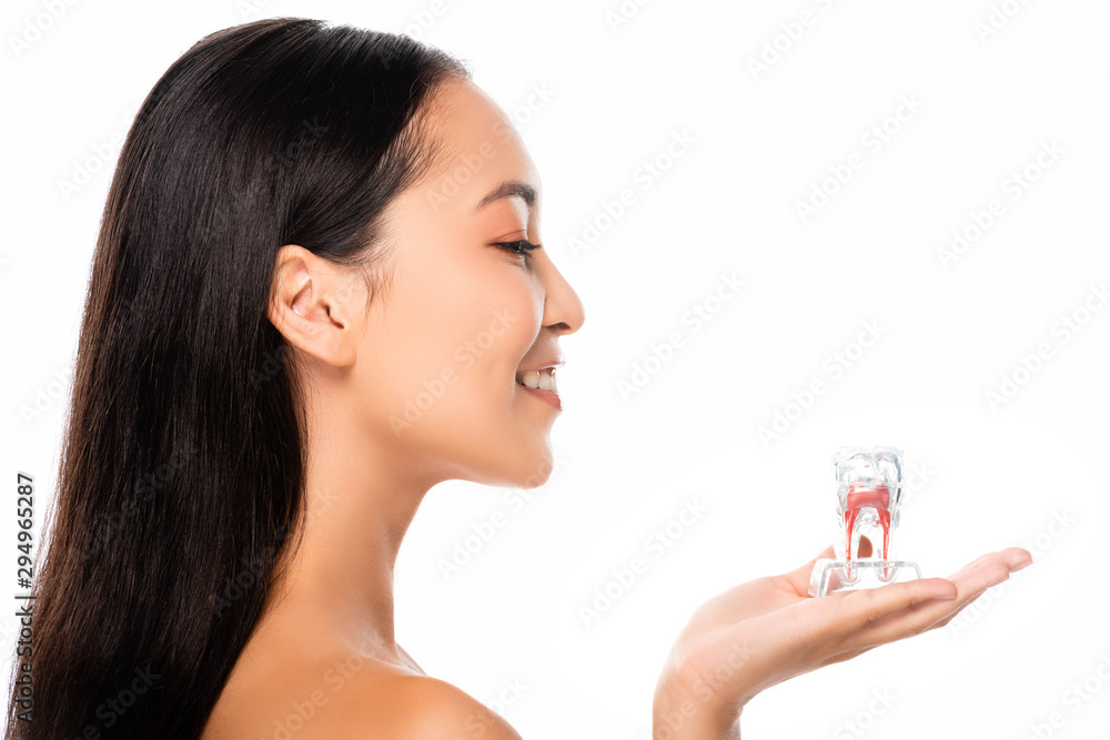 side view of happy naked asian woman holding tooth model isolated on white side view of happy naked asian woman holding tooth model isolated on white
