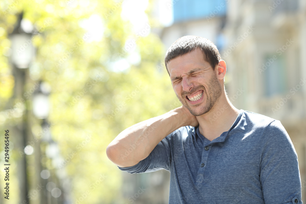 Fototapeta premium Stressed adult man suffering neck ache in the street