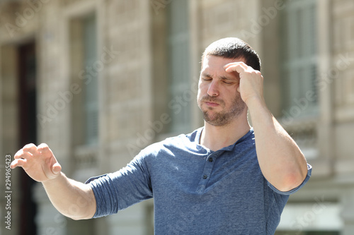 Dizzy adult man suffering headache in the street photo