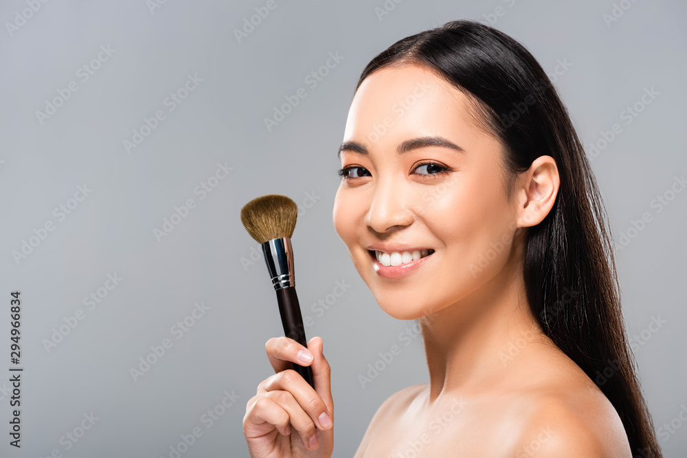 cheerful beautiful naked asian woman with cosmetic brush isolated on grey cheerful beautiful naked asian woman with cosmetic brush isolated on grey