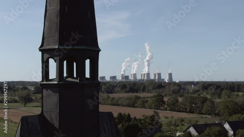 Church tower in Heinersbruck and Janschwalde Power Station in background, panning closeup, germany photo