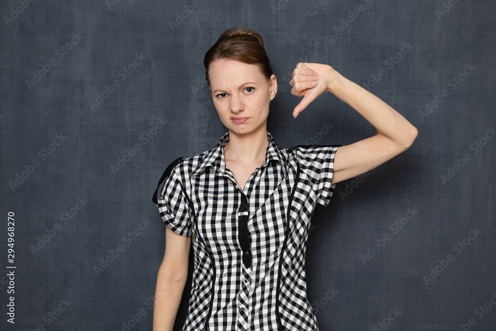Portrait of discontented annoyed girl showing thumb down gesture Portrait of discontented annoyed girl showing thumb down gesture