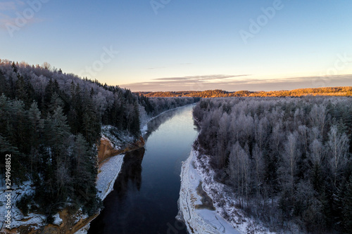 Winter landscape, sunrise over forest and river Gauja going trough. 