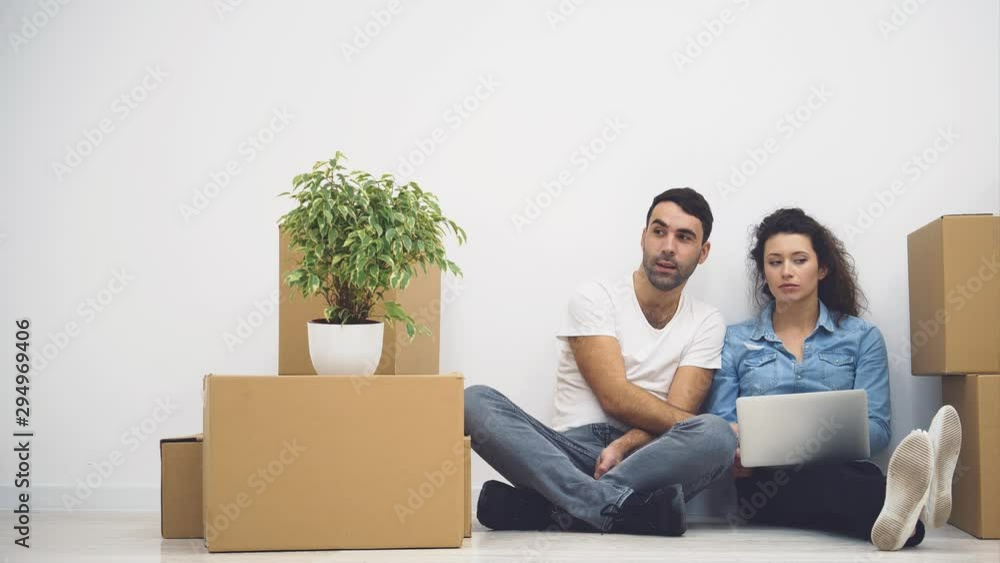 Young couple is moving to a new apartment together. They are thinking what to start from, looking at the screen of laptop. Action. Animation. 4K. Young couple is moving to a new apartment together. They are thinking what to start from, looking at the screen of laptop. Action. Animation. 4K.