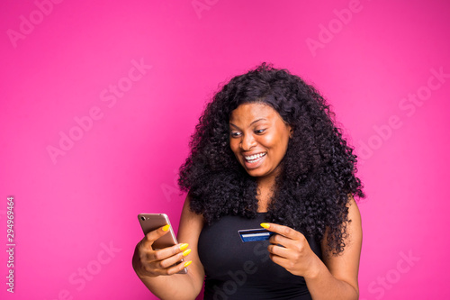 a beautiful young african nigerian lady feels happy what she is doing with her smart phone and credit card