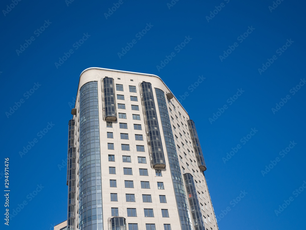 Modern high-rise building on a background of blue sky. Theme of modern geometric architecture and urbanization