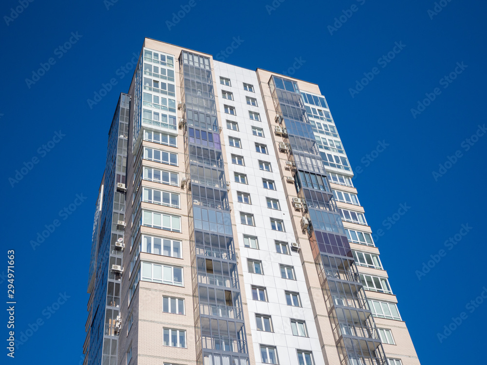 New residential building in the blue sky. View from below. Theme of modern geometric architecture and urbanization