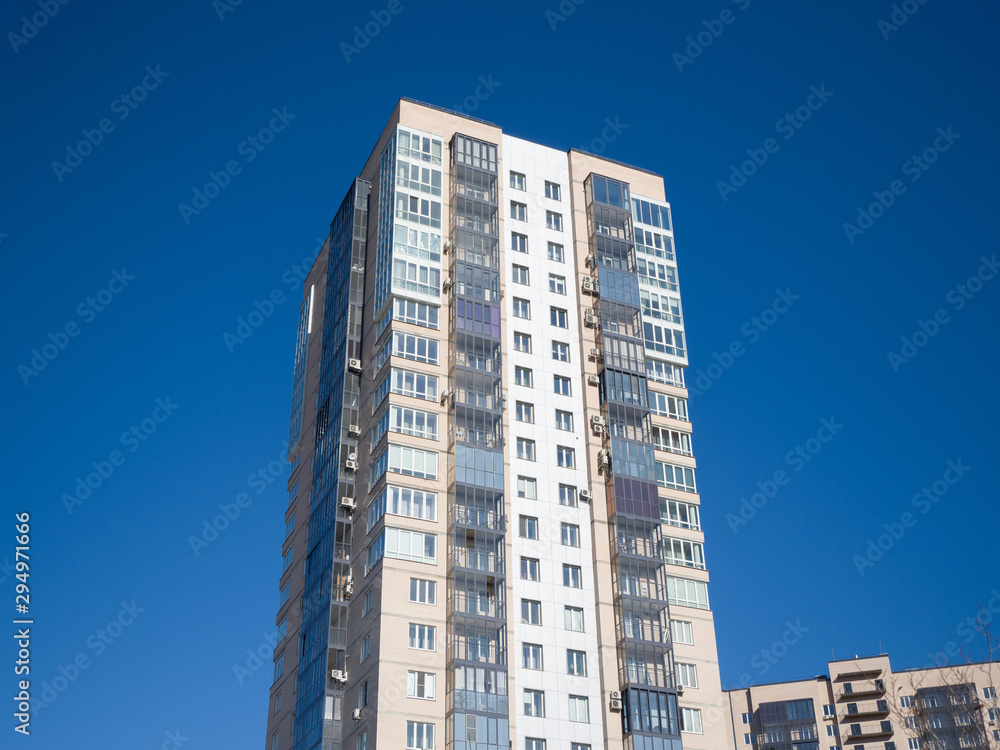 New residential building on a background of blue sky. Theme of modern geometric architecture and urbanization