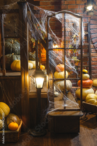 Festive mystical halloween interior. A lot of different pumpkins. Spider web, candles, spiders