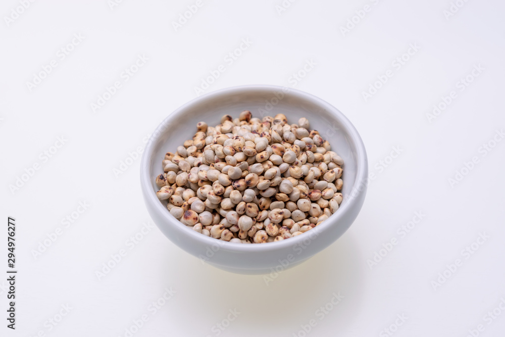 Uncooked raw Sorghum (also known as sorgo) in a white bowl, isolated on white background Uncooked raw Sorghum (also known as sorgo) in a white bowl, isolated on white background